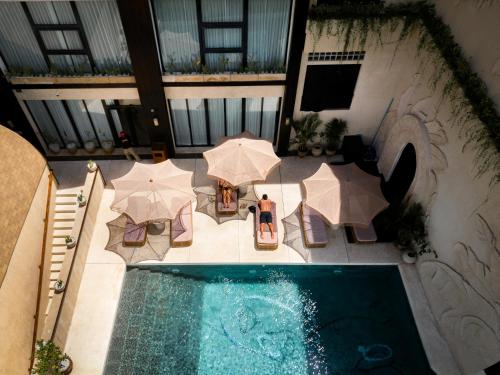 an overhead view of a swimming pool with umbrellas and tables at Sunny Samudra Boutique hotel Uluwatu in Uluwatu