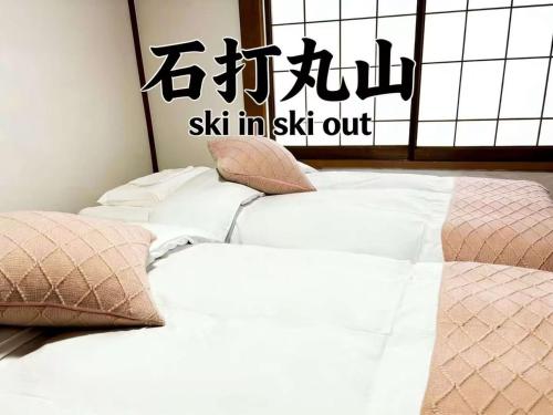 two white beds with pillows in a bedroom at 湯沢石打ホテルNozomi in Seki