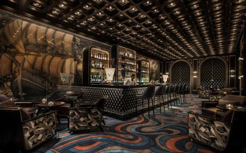 a bar in a restaurant with a man standing at the counter at Four Seasons Hotel Jakarta in Jakarta