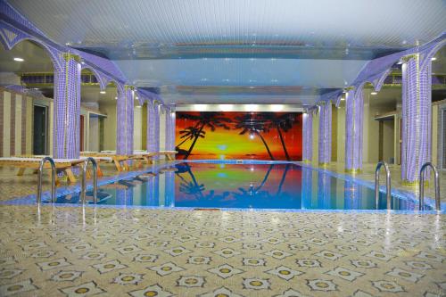 a swimming pool in a building with a painting on the wall at HON SAROY - immerse atmosphere in the epoch of the khans in Tashkent