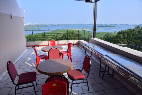 een balkon met tafels en stoelen en uitzicht op het water bij Majestic LAKEVIEW in Madurai