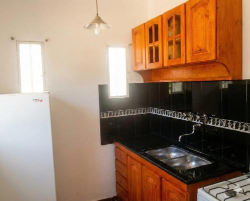 una cucina con armadi in legno e piano di lavoro nero di Brisas Serranas Departamentos a Villa Carlos Paz