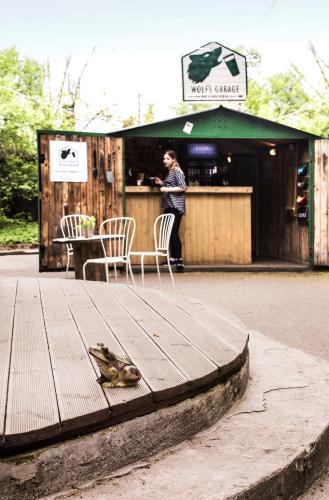a woman standing at a bar with a table and chairs at Downtown Forest Hostel & Camping in Vilnius