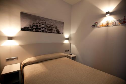 a bedroom with a bed and two lights on the wall at Hotel Ciutat De Sant Adria in Sant Adria de Besos