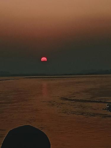 a sunset over the ocean with a red sun in the distance at Narayani view resort in Bharatpur