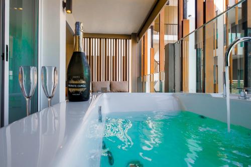 a bath tub with a bottle of wine and two wine glasses at G Hua Hin Resort & Mall in Hua Hin