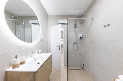 ein Badezimmer mit Waschbecken und Dusche mit Spiegel in der Unterkunft Apartman BILI in Solin