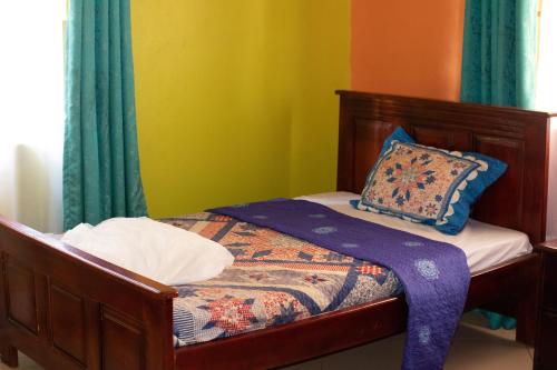 Un dormitorio pequeño con una cama con cortinas verdes. en Calmchaos Jinja, en Jinja