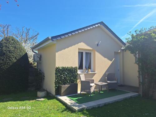 ein kleines Haus mit einem Tisch und Stühlen im Hof in der Unterkunft Charmante maisonnette équipée in Caudebec-lès-Elbeuf