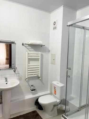a white bathroom with a toilet and a sink at Residence Keruen in Atyrau