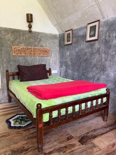 een slaapkamer met een houten bed en een rode deken bij Moksha eco villa Ella in Ella