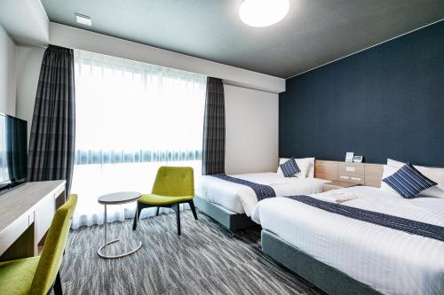 a hotel room with two beds and a tv at Shizutetsu Hotel Prezio Hakataekimae in Fukuoka