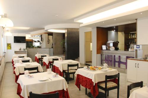 Un restaurante con mesas y sillas blancas y una cocina. en Hotel Salieri, en Legnago