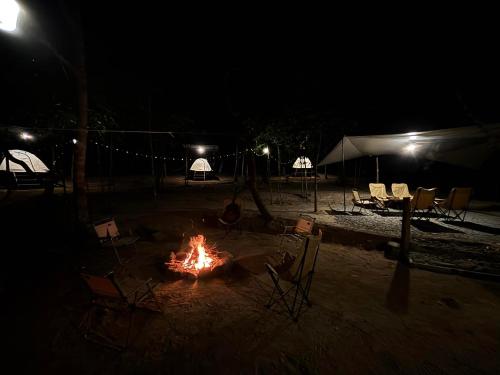 Ein Lagerfeuer im Sand mit Stühlen und Zelten in der Nacht in der Unterkunft Ko Kut Nature Camp in Ko Kood