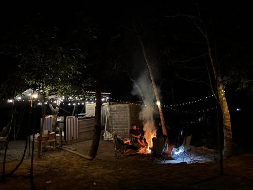 eine Person, die nachts um ein Feuer herum sitzt in der Unterkunft Ko Kut Nature Camp in Ko Kood