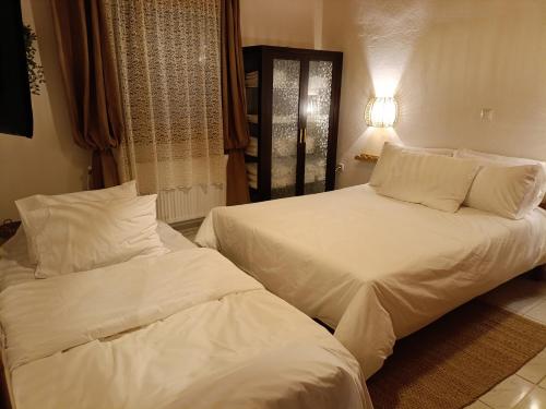 2 bedden in een hotelkamer met witte lakens en kussens bij Rooster Retreat in Aridaía