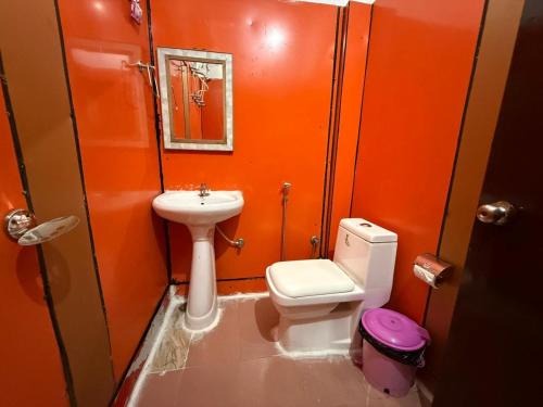 an orange bathroom with a toilet and a sink at Hotel Sunrise Inn & Restaurant, Kanatal in Chamba