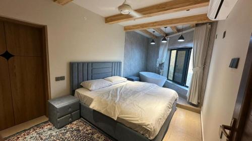 a bedroom with a bed and a bathroom with a tub at Bait Falaj Al Misfah Hospitality in Misfāh