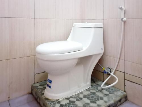 een wit toilet in een badkamer met een slang bij Hotel Intan Sampang Banyumas RedPartner 