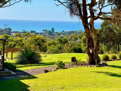 a park with a tree and the ocean in the background at Cooinda Retreats - The Residence in Victor Harbor