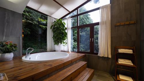 a bathroom with a tub and a large window at Yangshuo The Apsara Lodge in Yangshuo