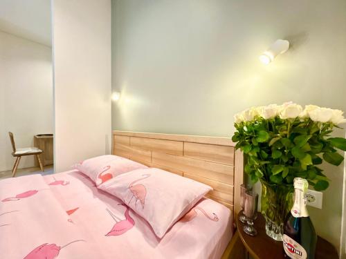 a bed with pink sheets and a vase of flowers at Lux Garden Appartments in Kharkiv