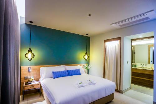 a bedroom with a large white bed and a blue wall at Fusion Suites Phuket Patong in Patong Beach