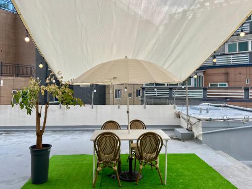 ein Tisch mit Stühlen und ein Sonnenschirm auf dem Dach in der Unterkunft 부산 광안리 비앤비 스테이 in Busan