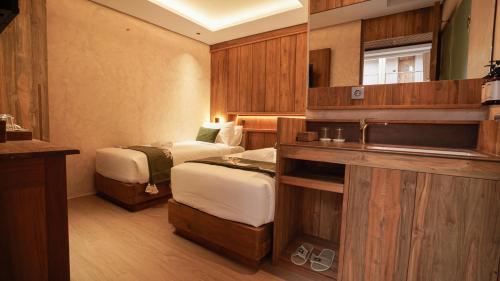 a hotel room with two beds and a television at Uma Tilu By Seken Living in Yogyakarta