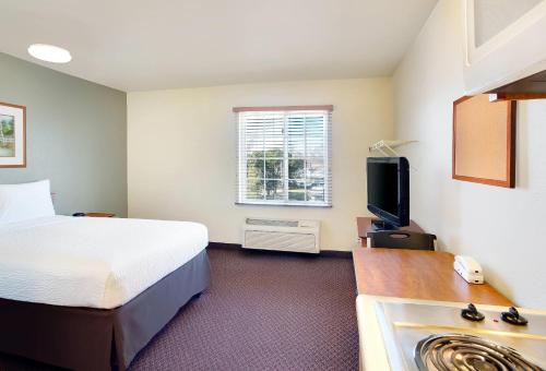 WoodSpring Suites Baton Rouge Airline Highway في باتون روج: غرفة فندق بها سرير وتلفزيون