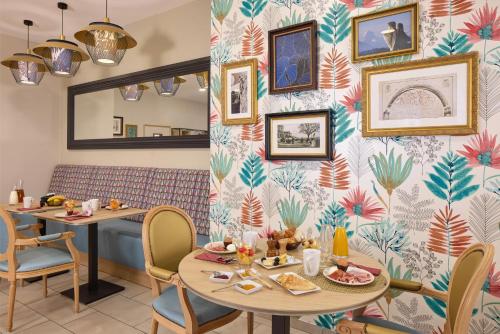Un restaurante con dos mesas y sillas y una pared cubierta de papel pintado. en Zenitude Quality Aparthotel Pau Porte des Pyrenees, en Pau
