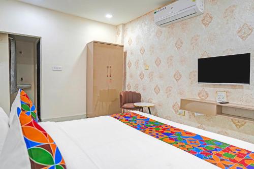 Un dormitorio con una cama y un televisor en la pared. en FabHotel Amrit Palace, en Indore