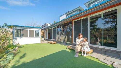 una mujer y un niño sentados en un banco frente a una casa en Gyepngju Camino Pool Villa, en Gyeongju