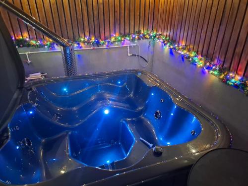 eine blaue Badewanne in einem Zimmer mit Weihnachtslichtern in der Unterkunft Cuibul de pe Deal Coșdeni Bihor 