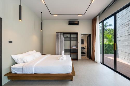 a bedroom with a white bed and a large window at Balance Village - exclusive villa with facility offered a full sense of privacy and resort style swimming pool in Ko Phangan