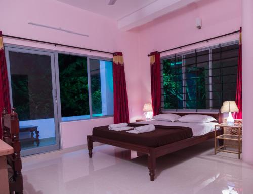 a bedroom with a large bed with red curtains at Orchid Lake View Homestay in Alleppey