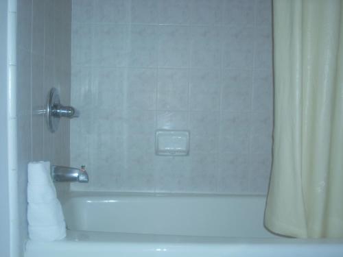 a bathroom with a shower with a tub and a sink at Economy Inn Seaside in Seaside