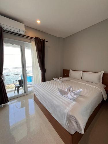 una camera da letto con un grande letto bianco e una grande finestra di Aluna Bay Hotel a Balige