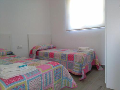 a room with three beds and a window at Apartamentos Noda in Playa de Santiago