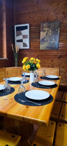 een houten tafel met borden en bloemen erop bij Cuore della Sila Apartment in Camigliatello Silano