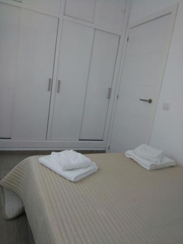 two white towels sitting on a bed in a room at Apartamentos Noda in Playa de Santiago