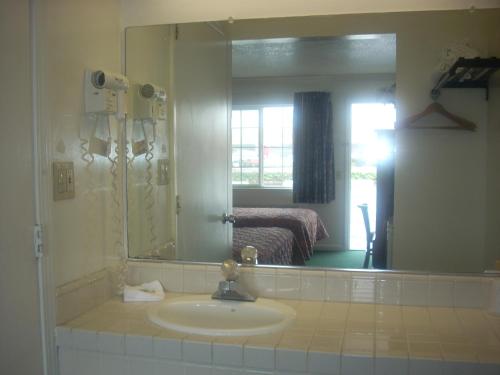 a bathroom with a sink and a large mirror at Economy Inn Seaside in Seaside