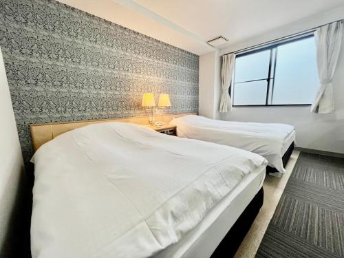 een slaapkamer met twee bedden en een raam bij サンシティーホテル山代 in Kaga