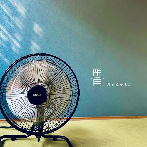 a black fan sitting in front of a blue wall at 宿えんがわーおもや in Tokorozawa