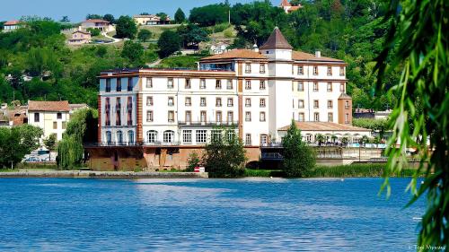 un gran edificio junto a una gran masa de agua en Hôtel & Restaurant Le Moulin de Moissac, en Moissac