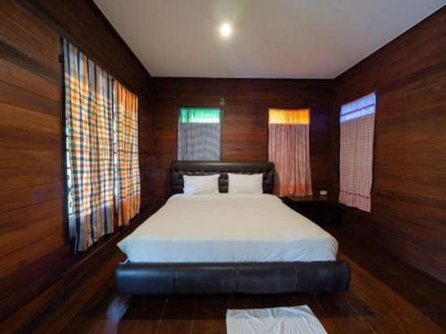The Frog Khao Yai Resort في Ban Tha Chang: غرفة نوم بسرير وجدران خشبية ونوافذ