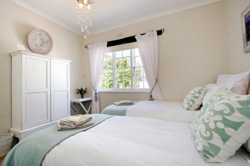 a bedroom with two beds and a window at Hout Bay Beach Cottage in Hout Bay