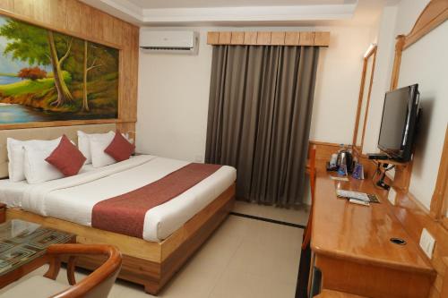 Una habitación de hotel con una cama, un escritorio y un televisor. en skypalace hotel, en Kannur