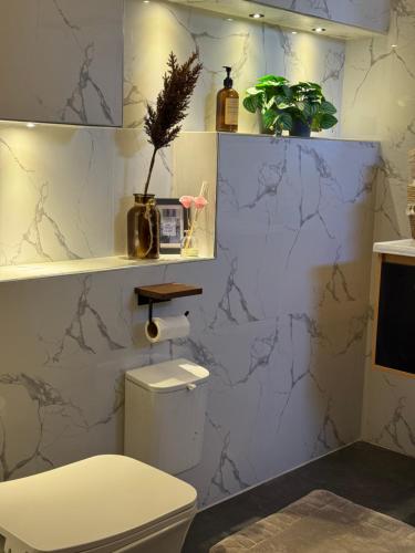 een badkamer met een wit toilet en marmeren muren bij Bonbon Beach House in Liloan