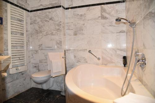 a bathroom with a white tub and a toilet at Altstadthotel Garni Schlundhaus & Rautenkranz in Meiningen